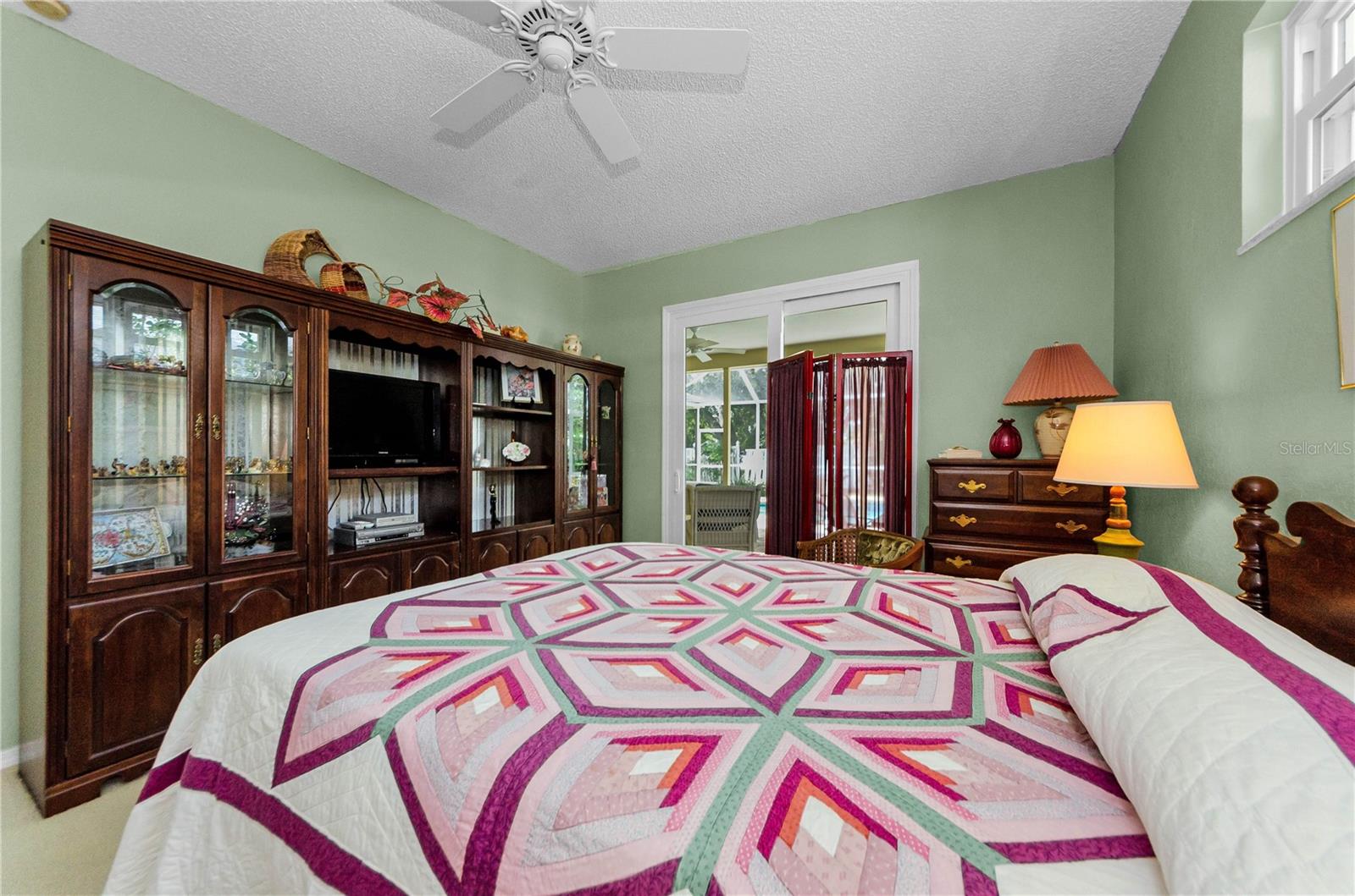 Primary bedroom in this split plan home, with sliders out to pool.