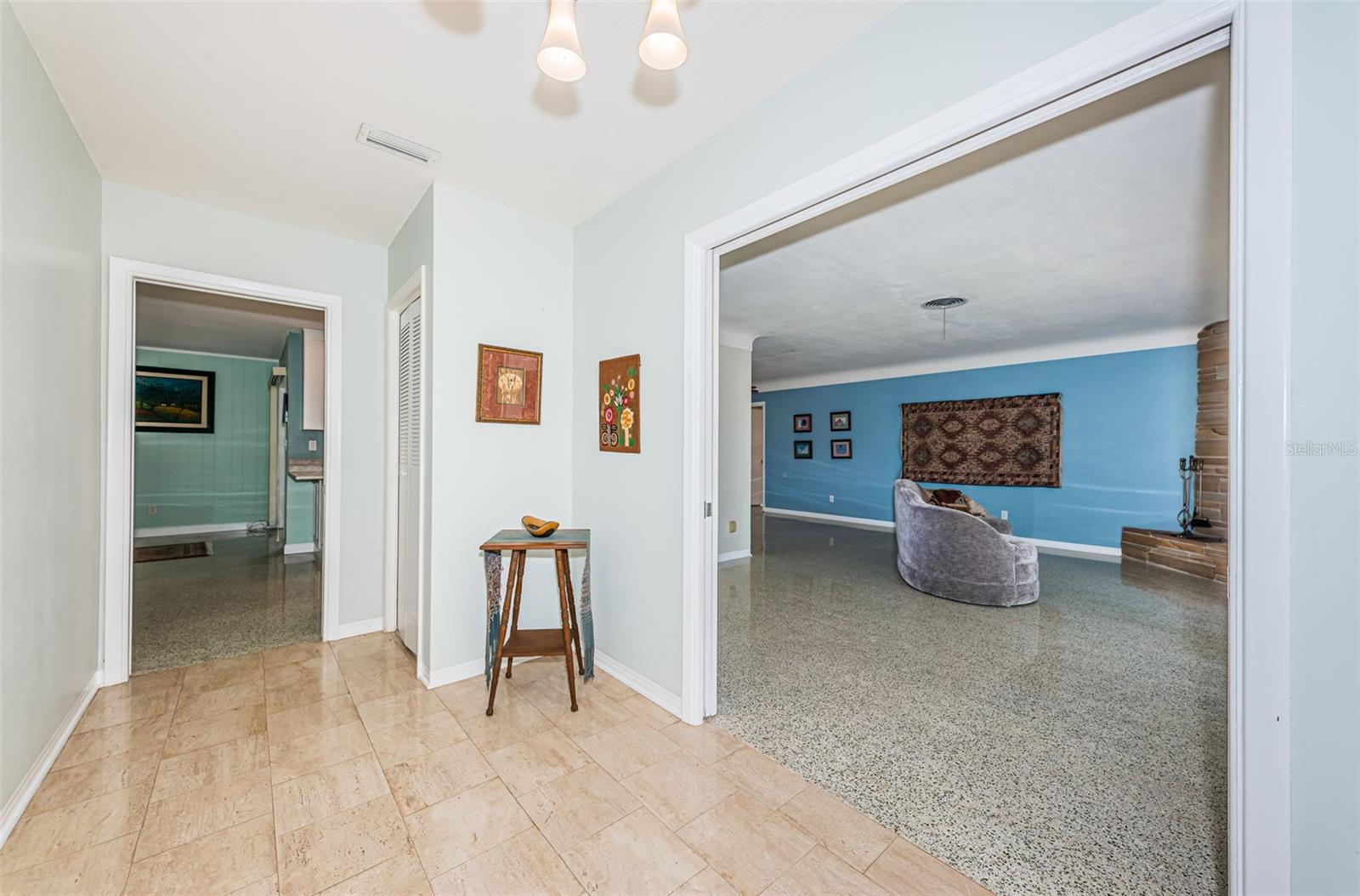 Foyer with marble flooring and picket doors that can close to provide privacy to the living room on right.