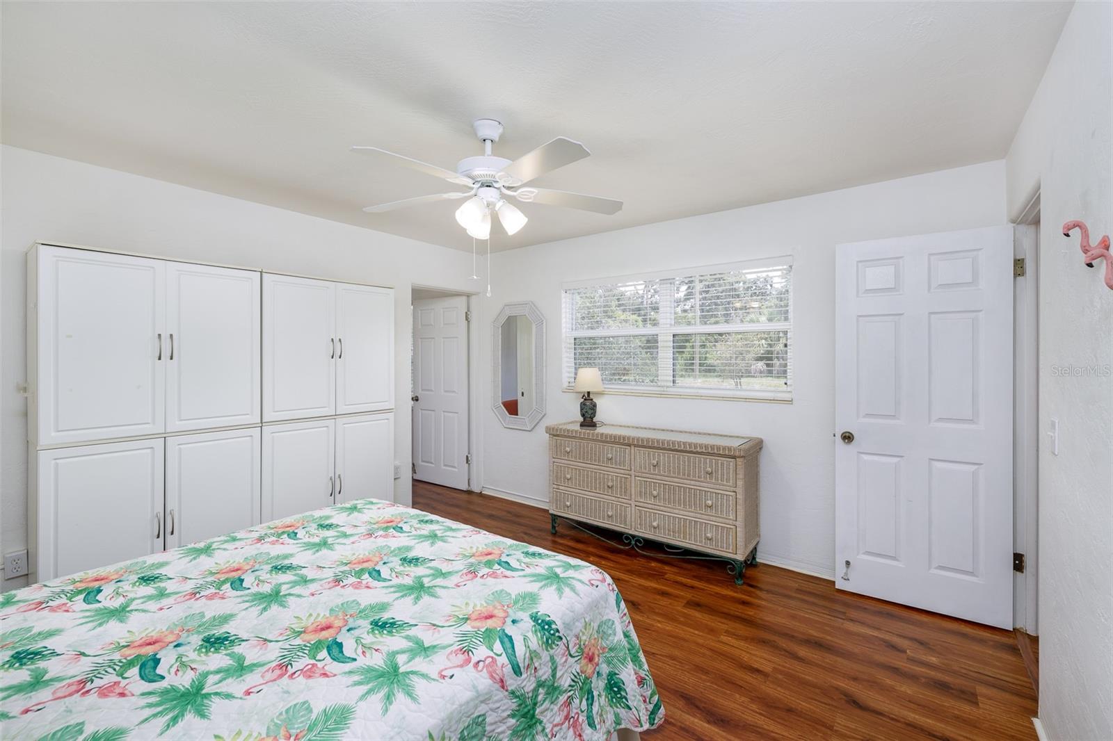A large window fills the room with soft daylight while ample cabinetry and a full dresser ensure clutter-free living.