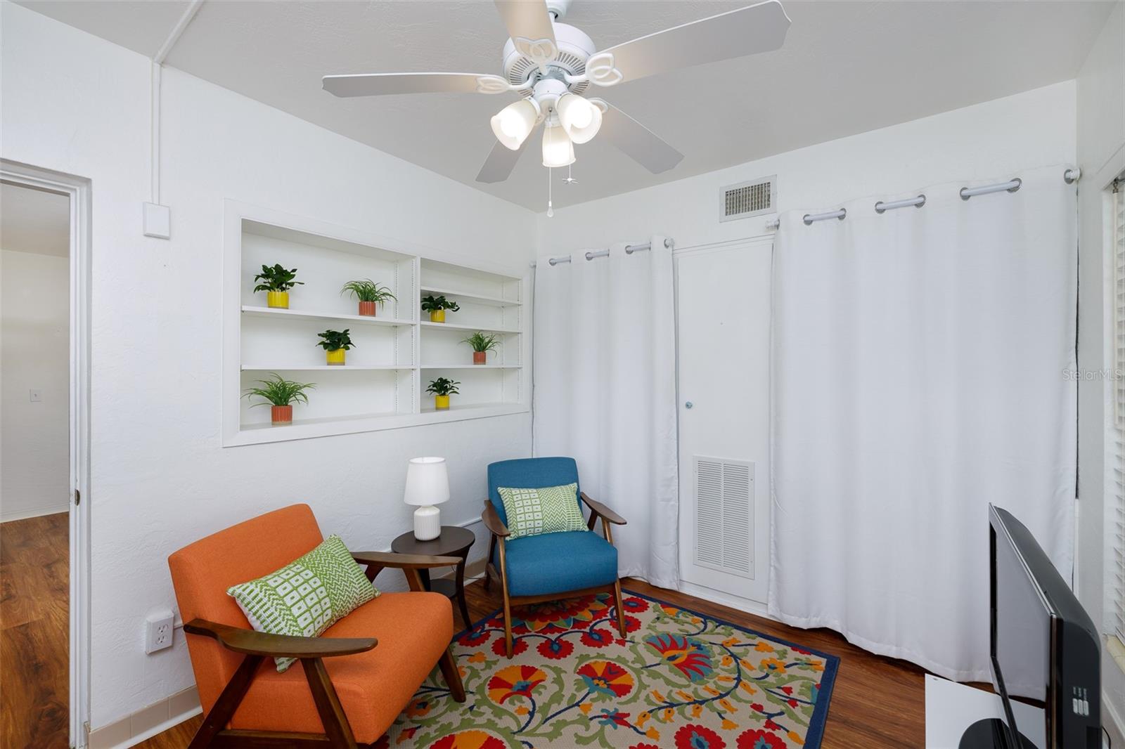 Fresh white walls, a ceiling fan, and built-in shelving make this the perfect spot to read, relax, or enjoy a good conversation.