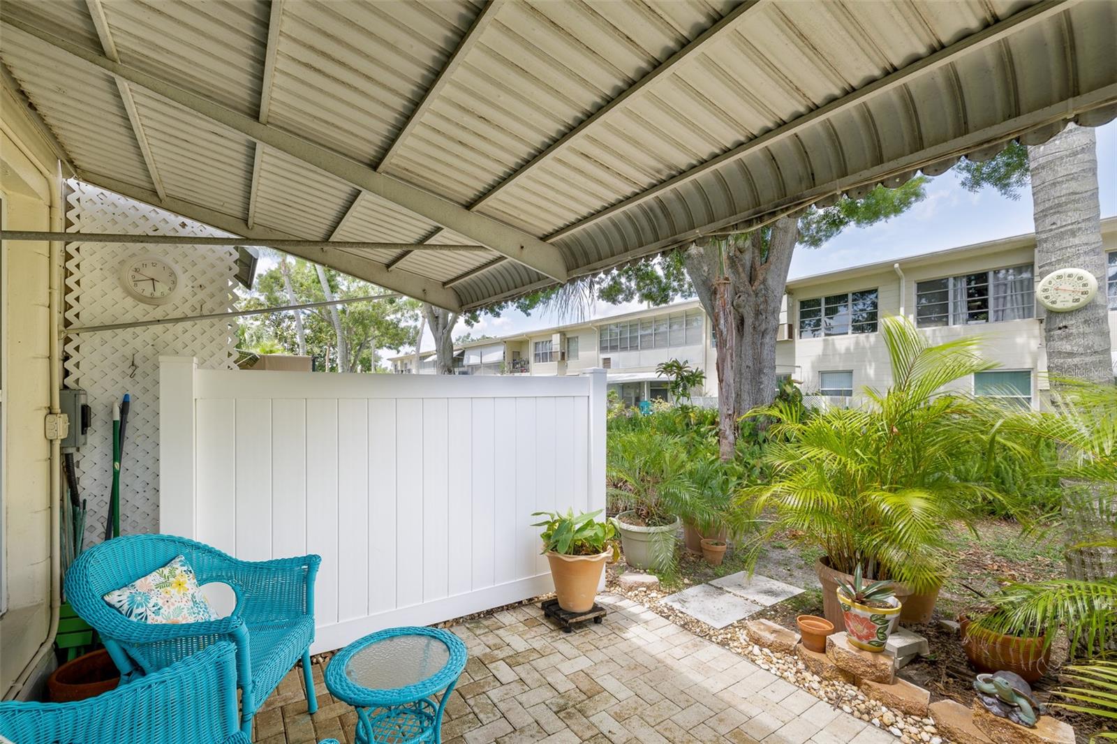 The rear patio is both private and lush, offering the perfect mix of sunshine and shade, framed by greenery and enhanced with decorative potted plants.