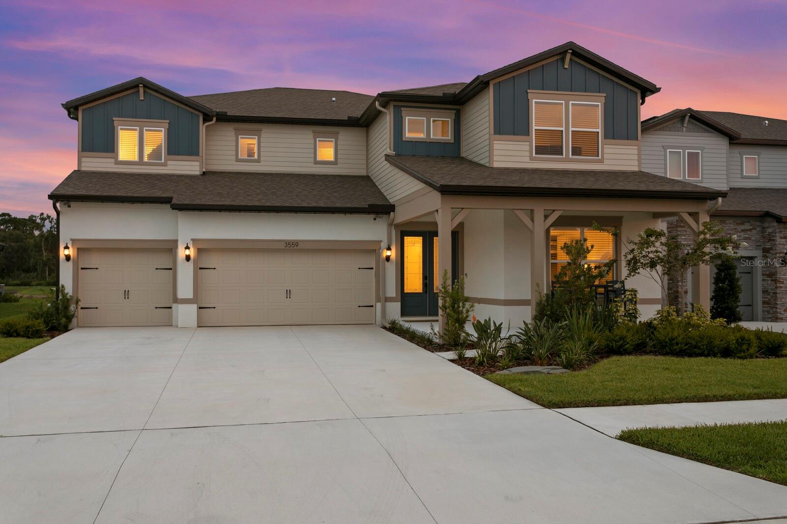 Front exterior with oversized driveway at twilight
