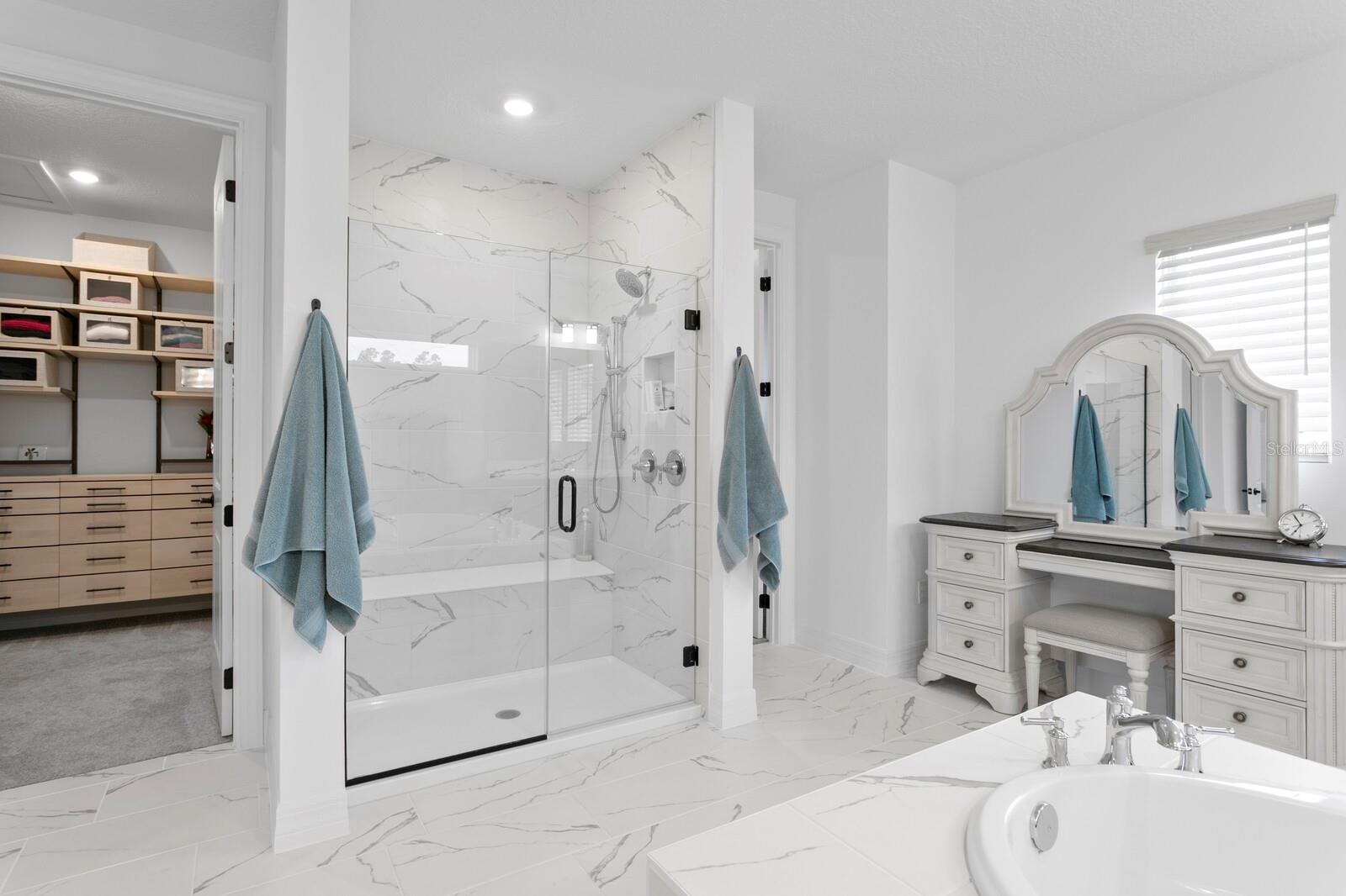 Primary ensuite with closets on each side of the walk-in seamless shower