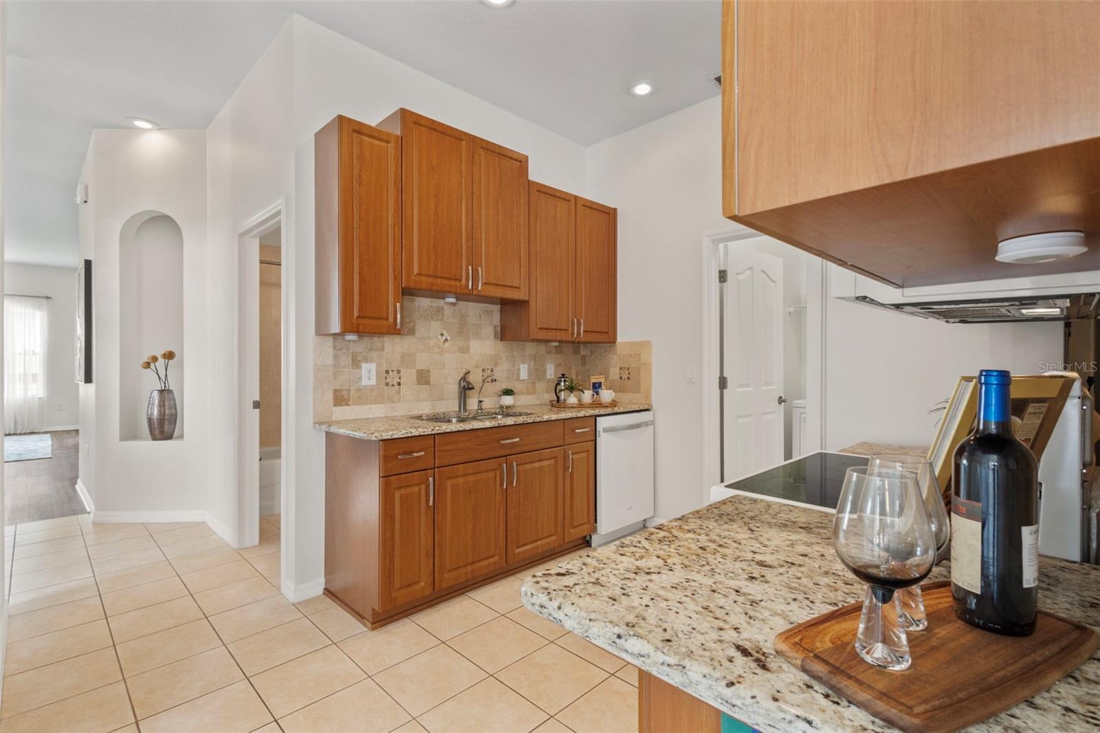 kitchen with warm wood cabinets, upgraded tile backsplash & granite counters