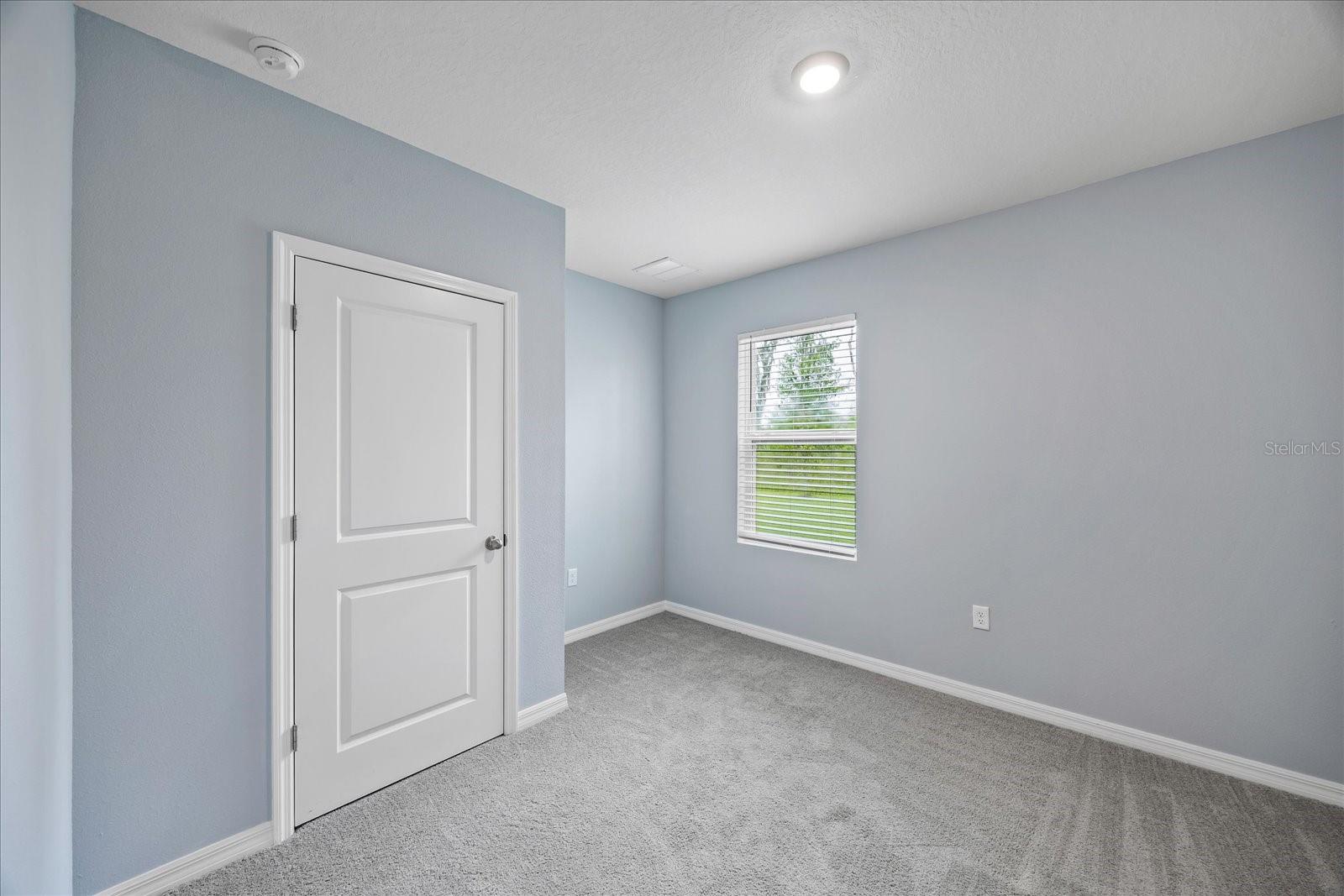 Lower level bedroom with access to full bathroom across the hallway
