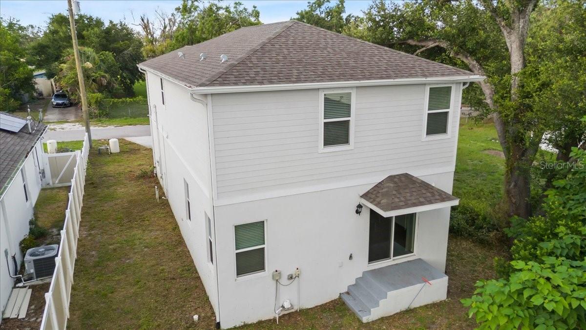 Back of home with covered patio and steps leading to backyard.