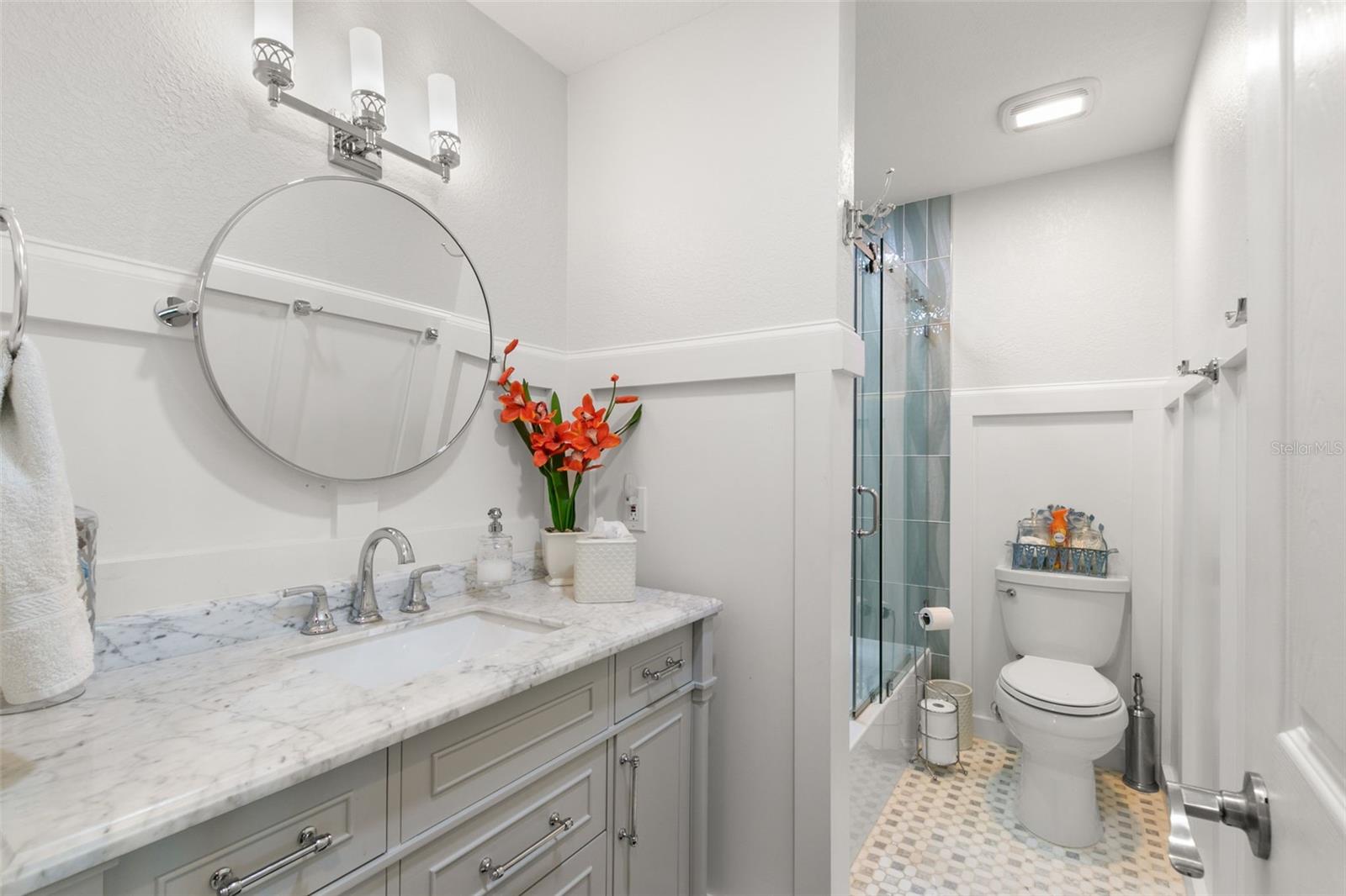 Guest bathroom with single sink, tile countertops, chair rail thru out bathroom with bath tub/shower and lots of storage