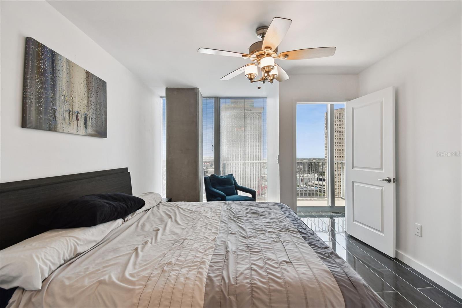 Wake up to sweeping skyline views in this light-filled primary bedroom featuring floor-to-ceiling windows and balcony access.