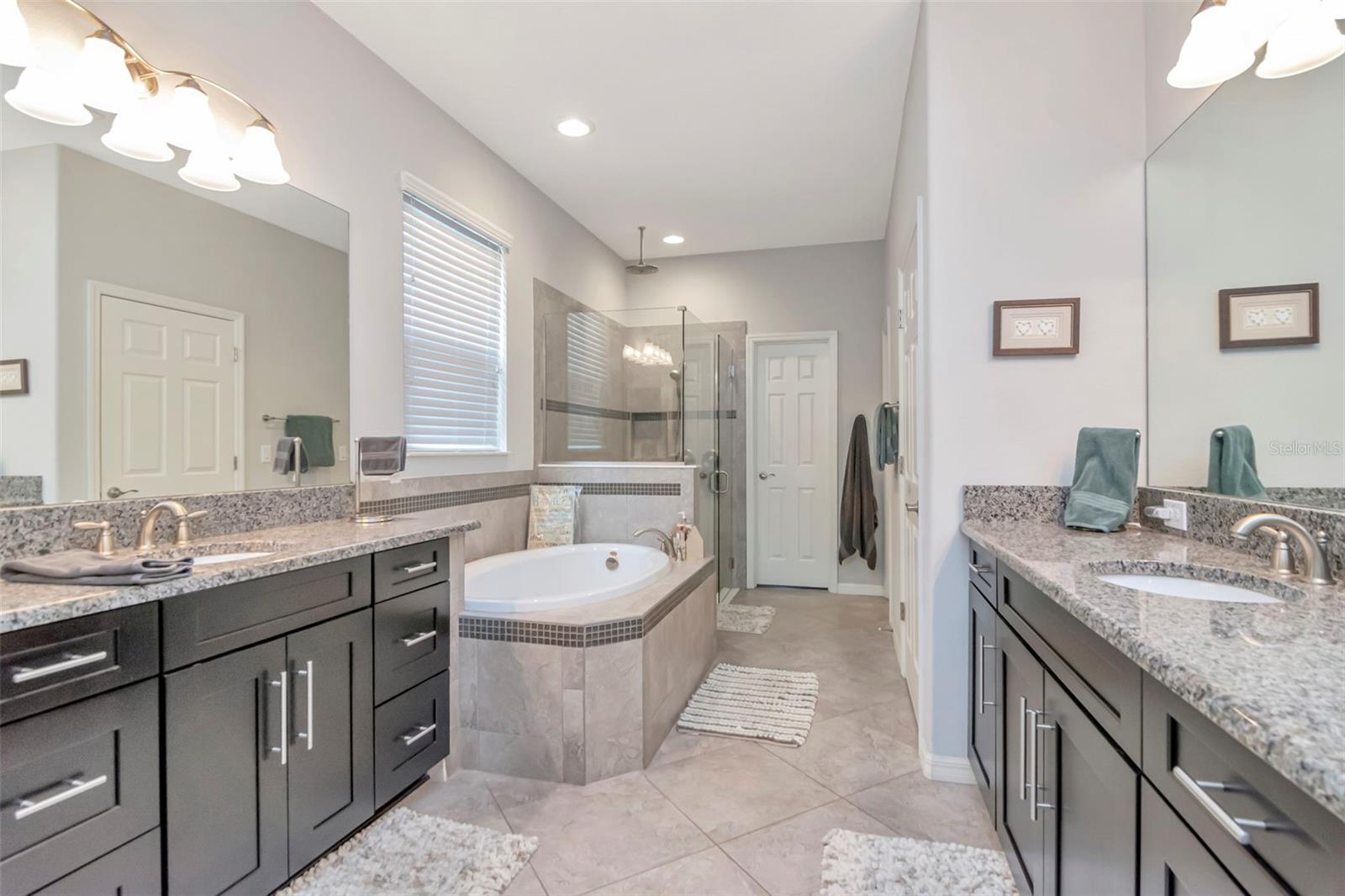 Primary Bathroom with dual sinks, makeup area, soaking tub and separate shower, private commode, and 2 walk-in closets