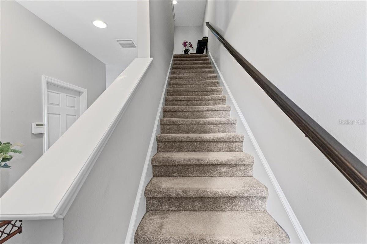 Modern staircase with sleek railings leads to private upstairs bedrooms