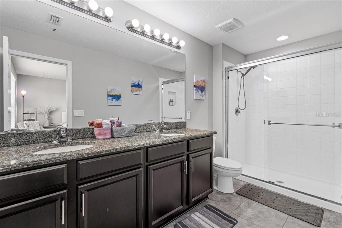 right, airy en-suite bathroom featuring dual vanities and a walk-in shower.