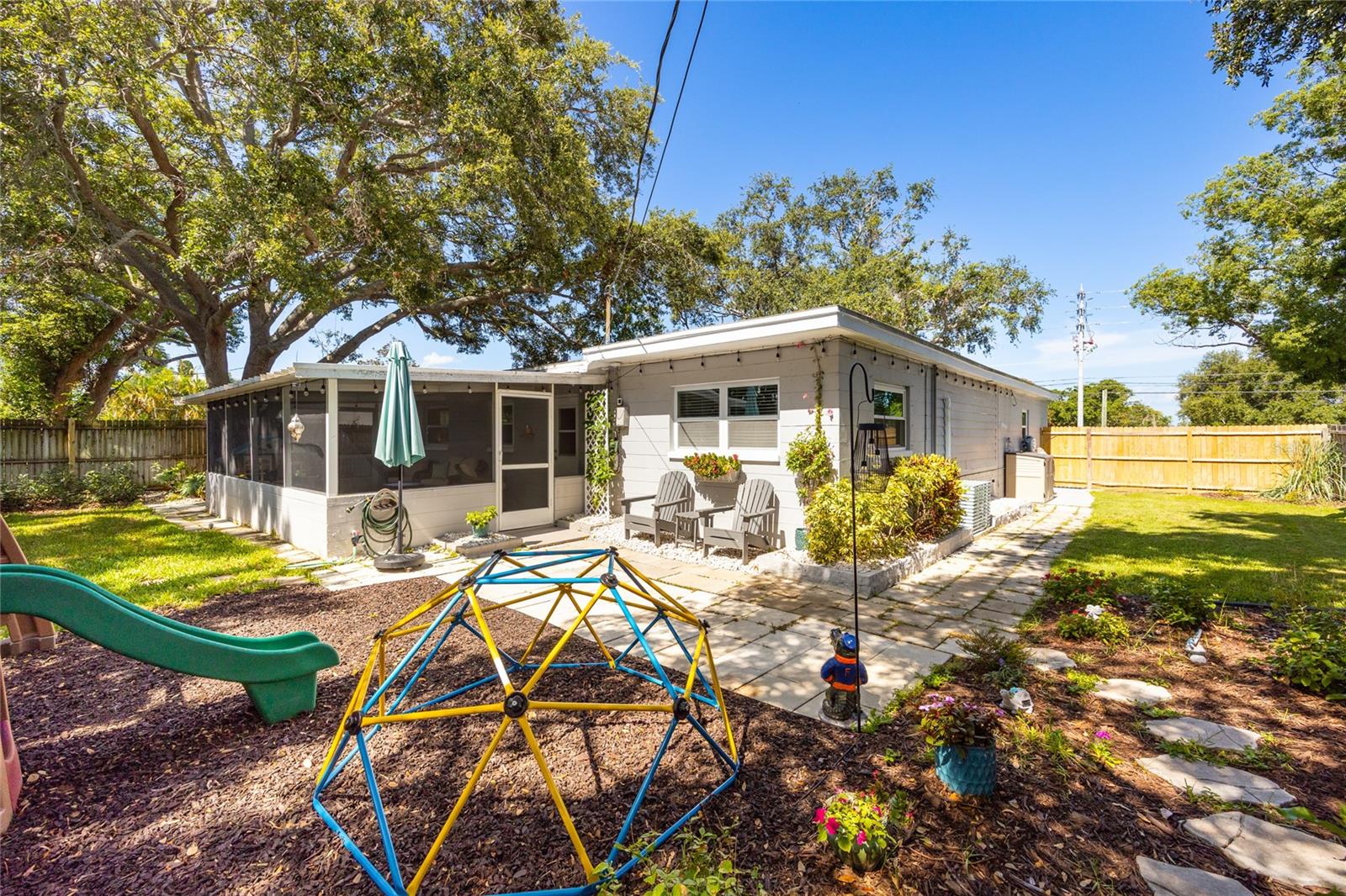 Fully fenced yard with room to run and play under the shade of a majestic oak tree—plus a screened porch and garden beds!