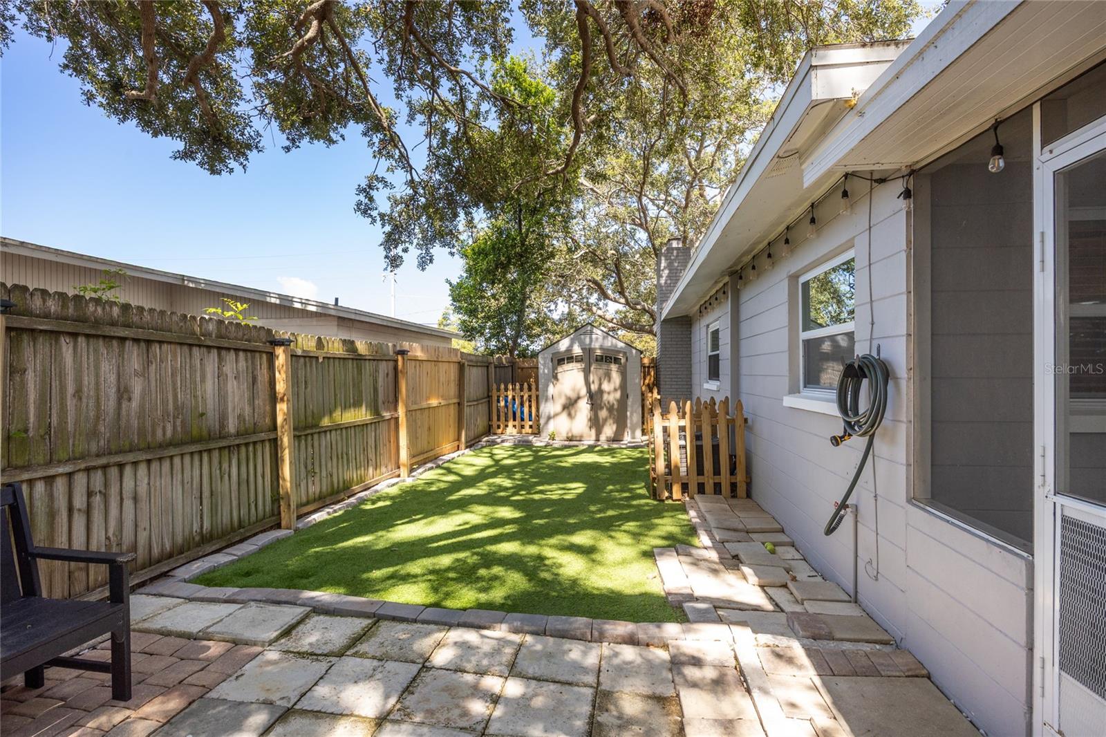 A gated side yard with synthetic turf—ideal for pets, a play zone, or a tidy low-maintenance escape.