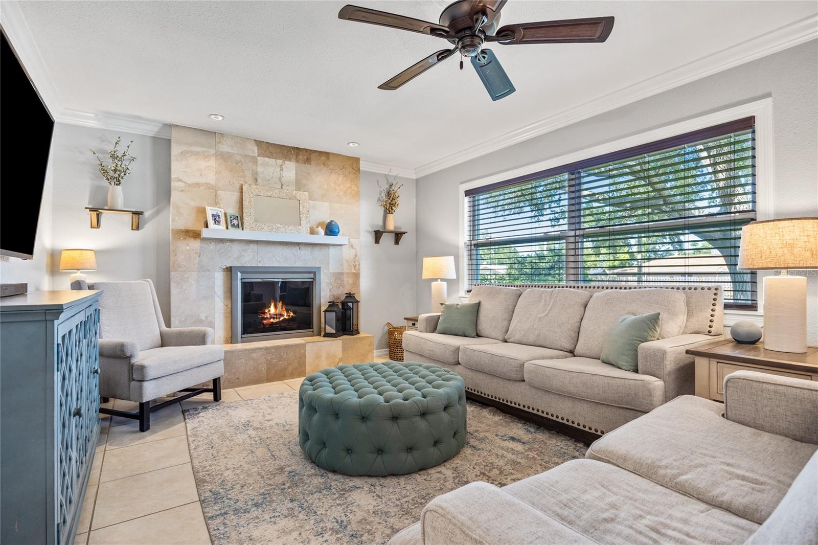 Cozy up by the fireplace in this inviting living space, accented by natural light and serene views through a picture window.