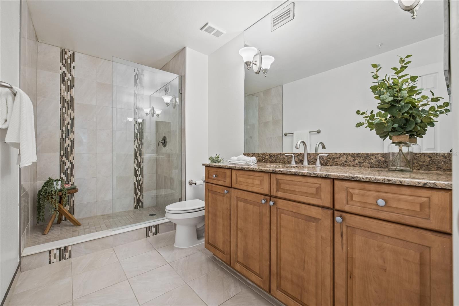 Stylish Ensuite Bathroom. Features warm wood cabinetry, a granite countertop, and sleek fixtures for a polished, modern look.