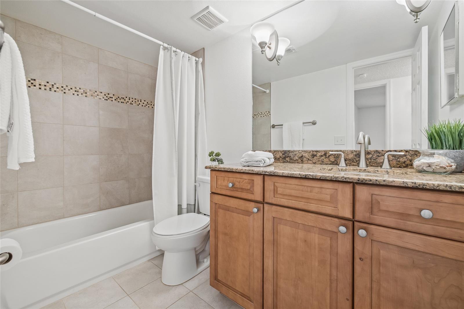 Contemporary Second Bathroom. Offers a granite countertop, modern fixtures, and a tiled tub/shower combo with stylish mosaic accents.