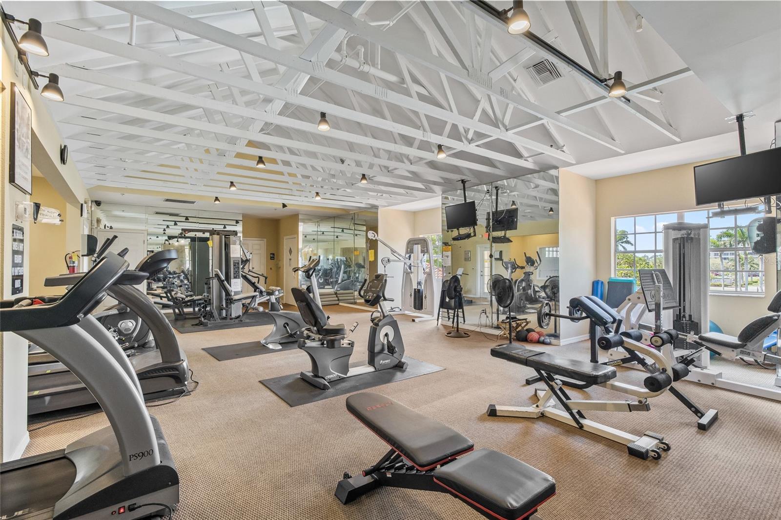 The expansive gym space with mirrored walls, multiple machines, and natural light for energizing workouts.