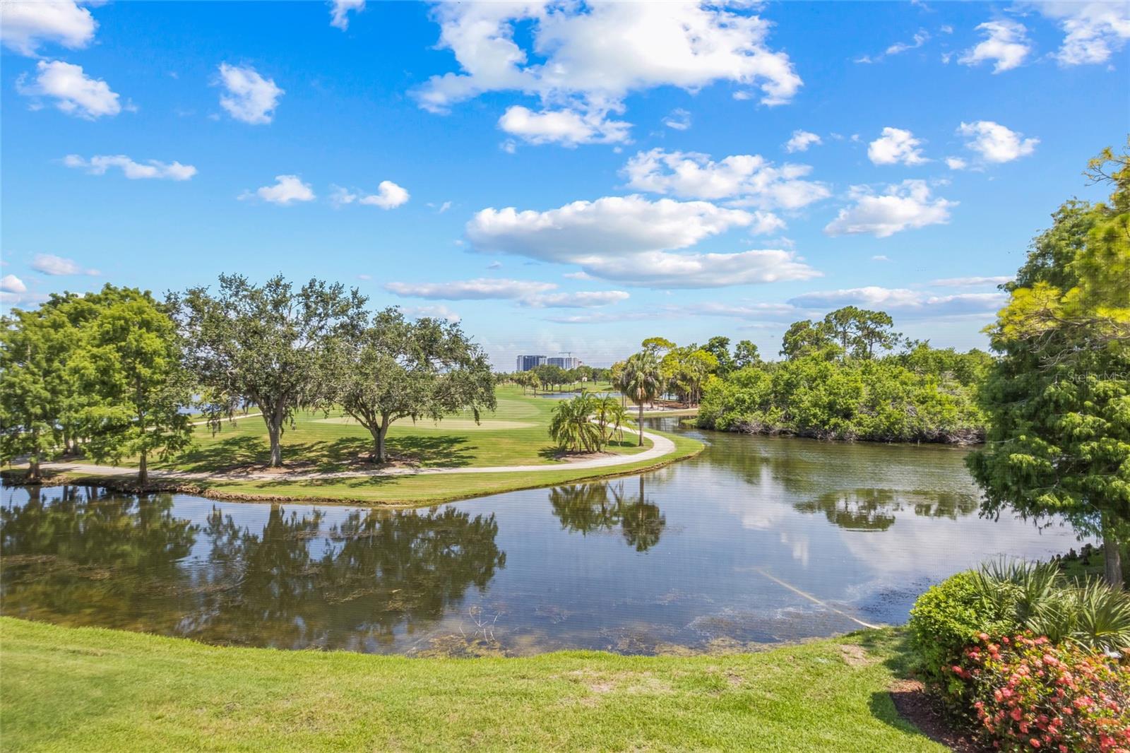 Lush Ground-Level View of Golf Course and Waterway. Enjoy vibrant landscaping, tranquil water reflections, and sweeping views of the fairway—right from the beautifully maintained grounds below.