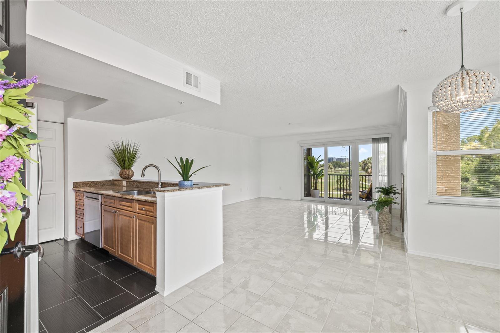 Light-Filled Open Living Space. Expansive tile floors and large windows create a bright, airy living area with direct access to the screened-in lanai.