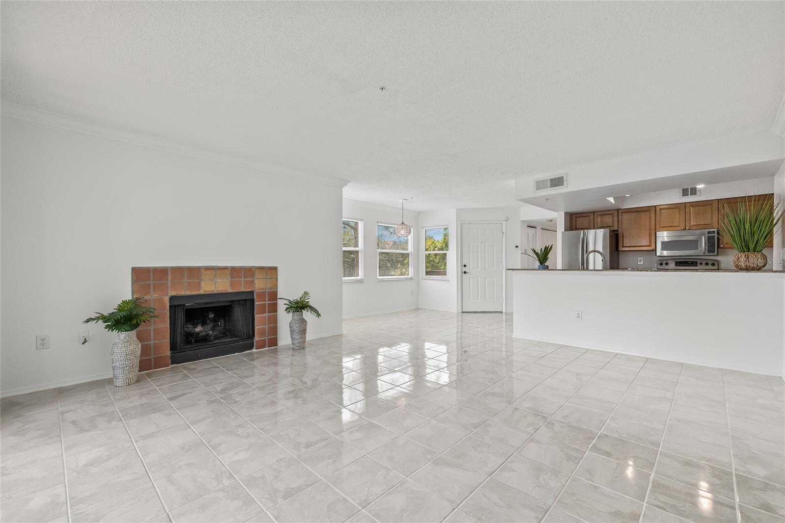 Spacious Open Layout with Fireplace. The living room flows seamlessly into the kitchen and dining area, highlighted by a cozy wood-burning fireplace and abundant natural light.