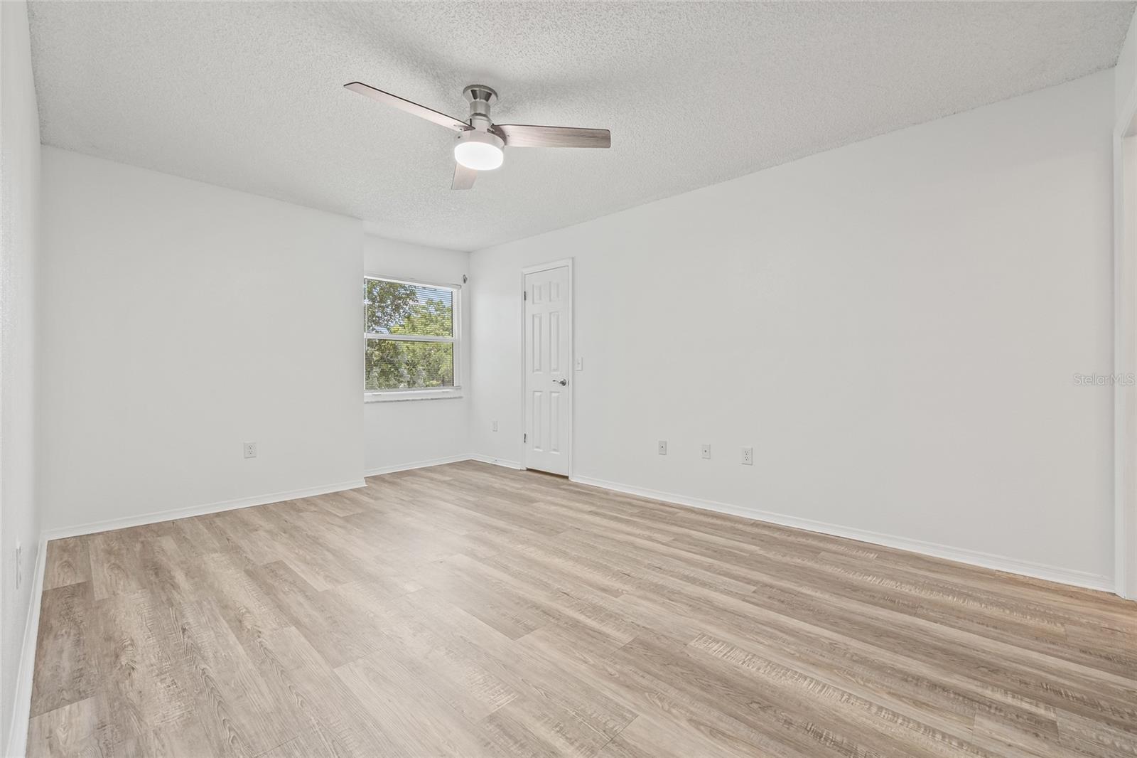 Spacious Primary Bedroom with Walk-In Closet. This generously sized retreat features updated flooring, a ceiling fan, and abundant natural light.
