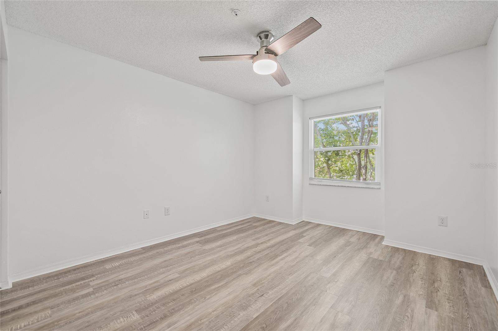 Bright and Serene Guest Bedroom. Features updated flooring, neutral tones, and a ceiling fan for year-round comfort.