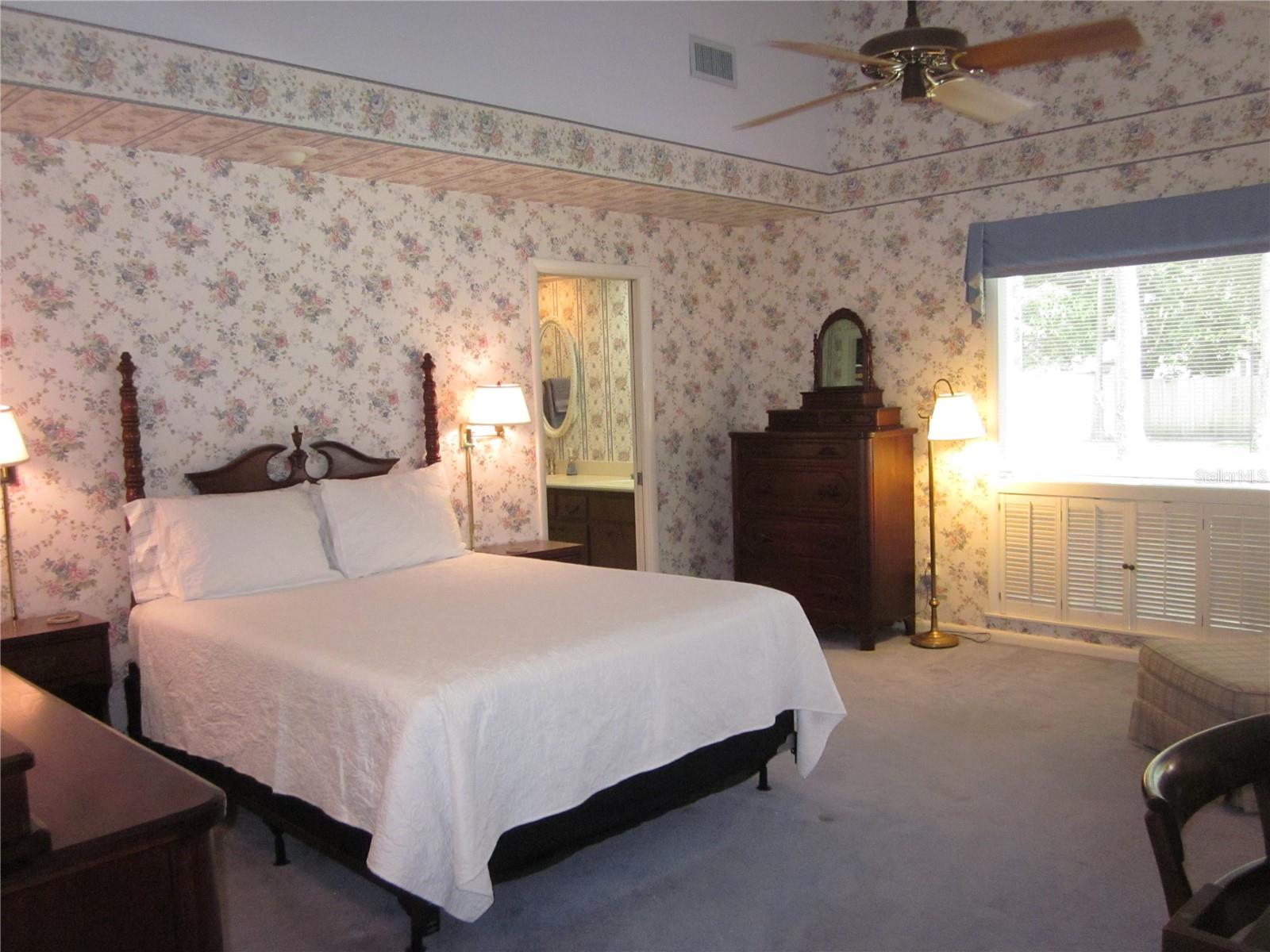 Primary/master bedroom with volume ceiling & large windows to the yard & pool