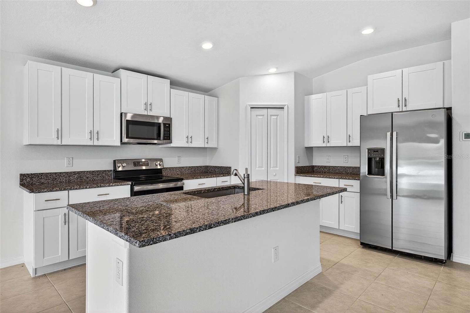 Stainless steel appliances, granite countertops throughout, white shaker cabinetry and closet pantry.