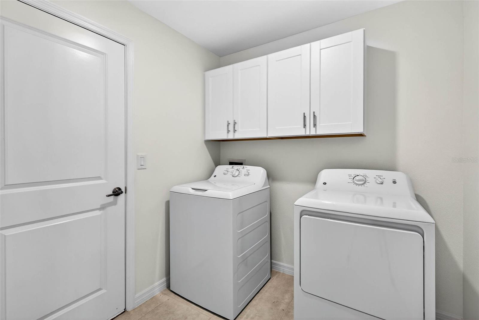 Laundry has additional storage cabinetry and access to the garage