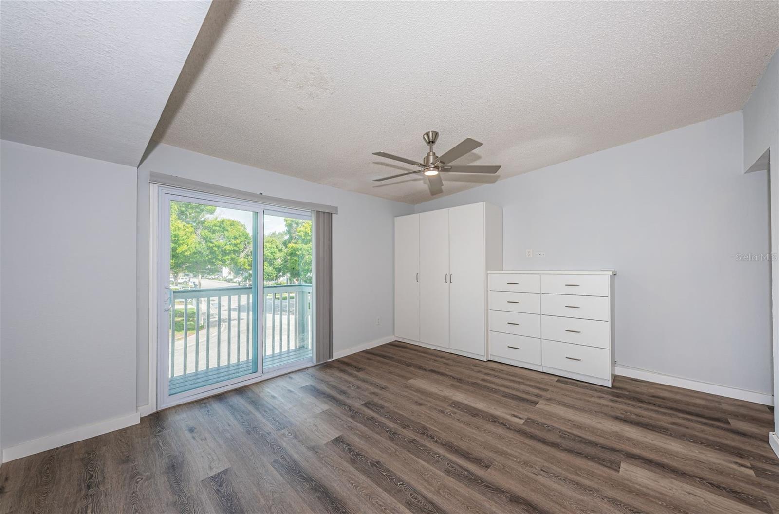 Master bedroom w/ closet/drawers, newer fan & impact slider leading to front porch