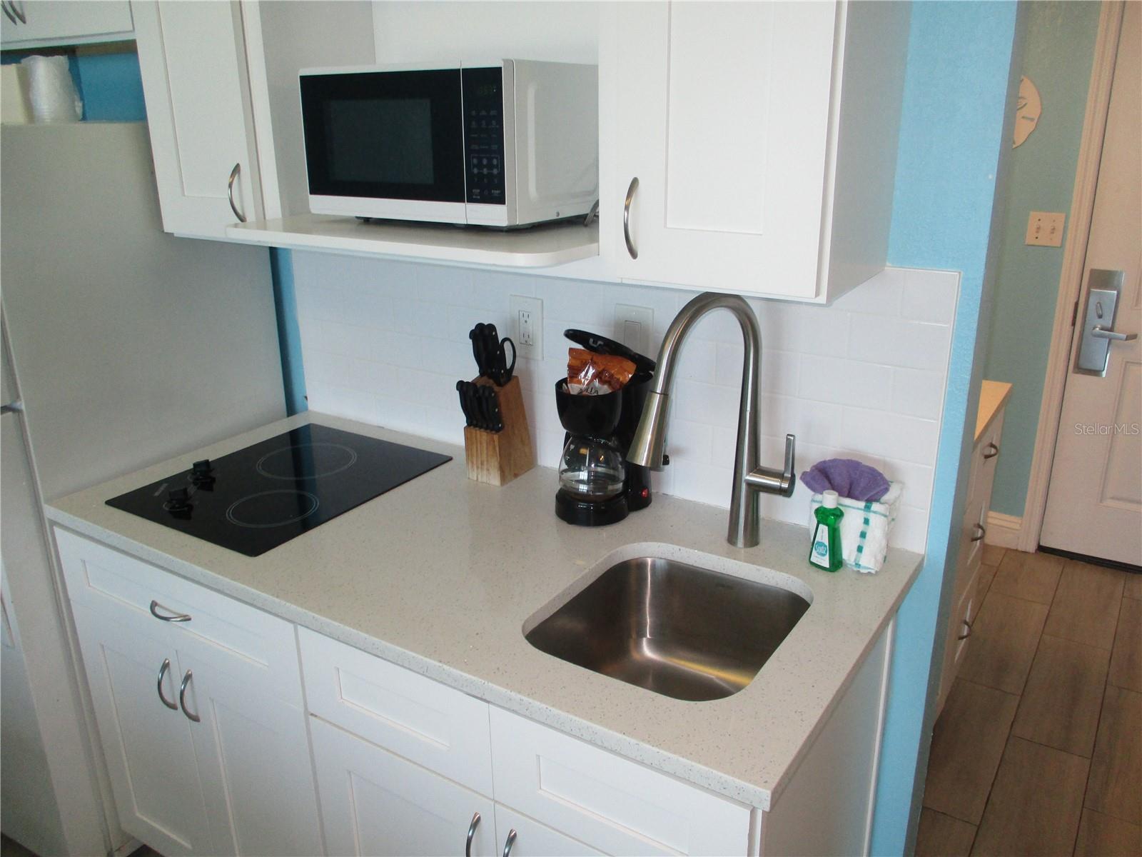 Stone counter with stovetop and microwave oven.