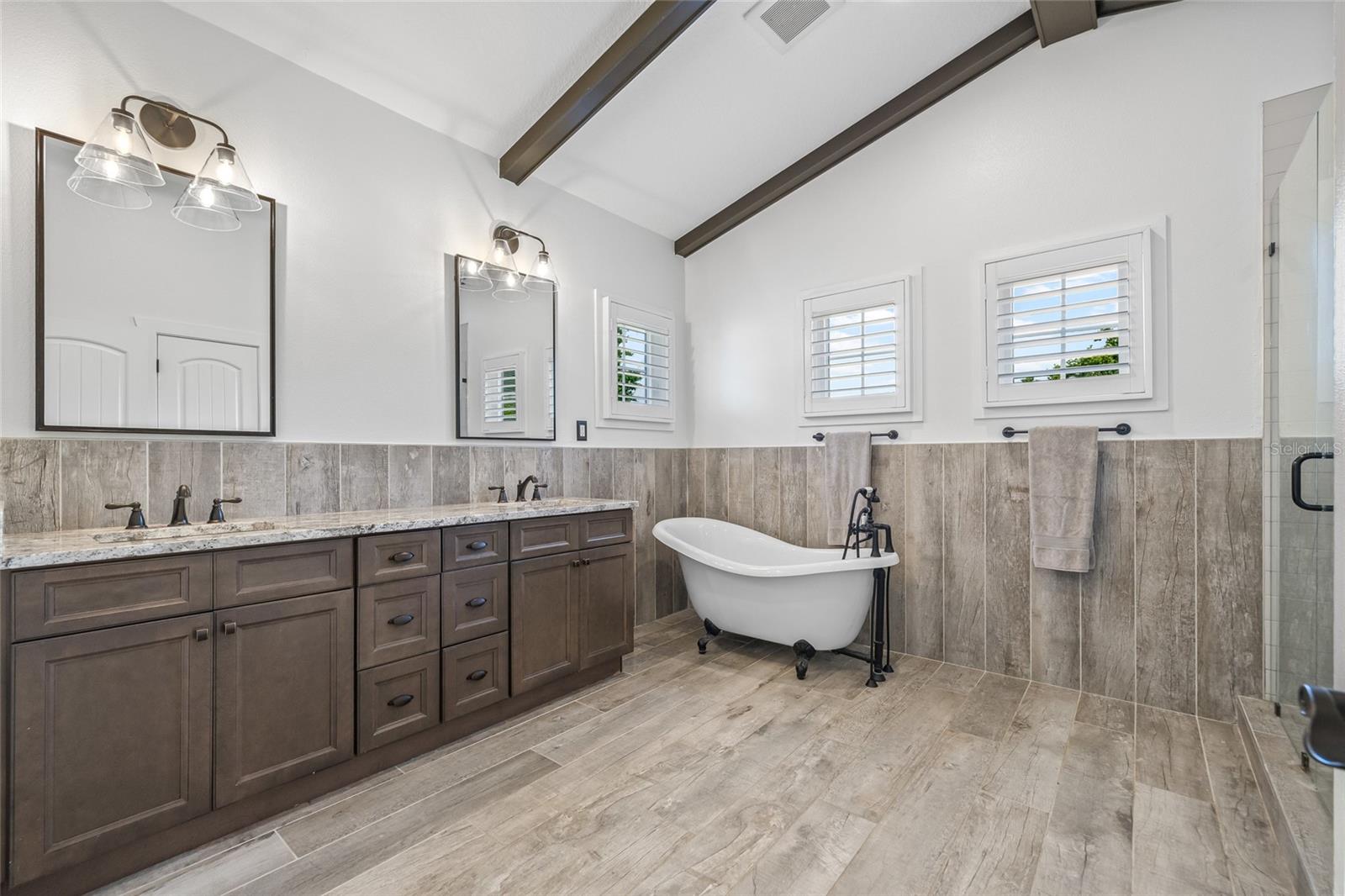 Exposed-beam, peaked ceilings in the primary bathroom.