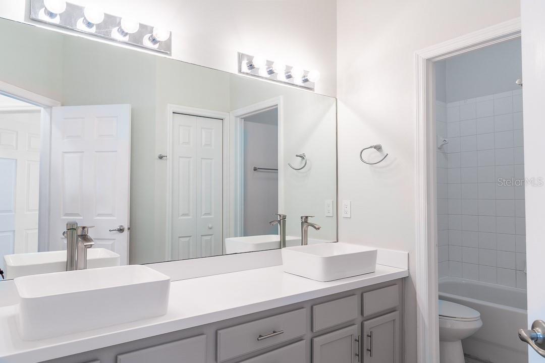 Hallway bathroom with dual sinks and a dual shower head for the shower