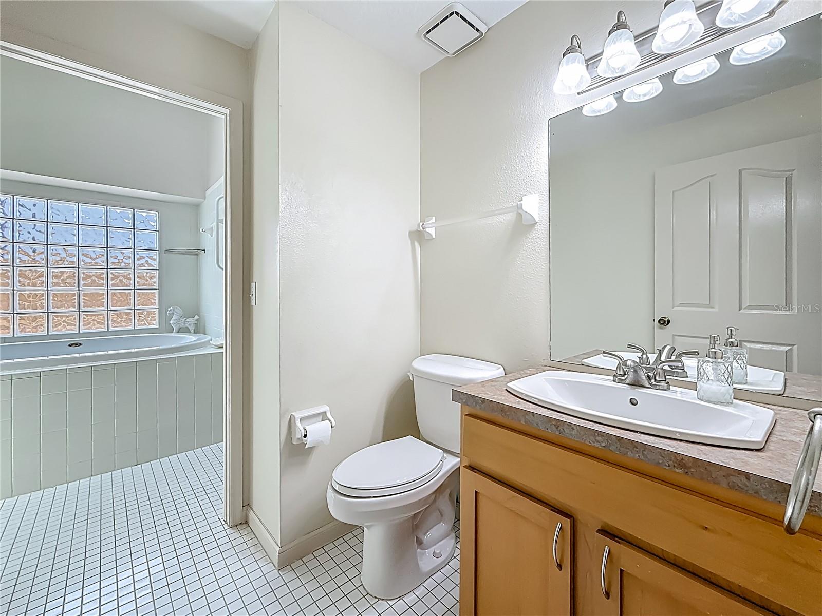 Hall bath, part of the Jack n' Jill bath that bedrooms 2 & 3 share. There is a door - from & to bedroom 2, to the left of the garden tub. To the right of the garden tub is another vanity, with a single sink with make-up area, along with a linen closet and the door to/from Bedroom 3. There is also a skylight over the tub.