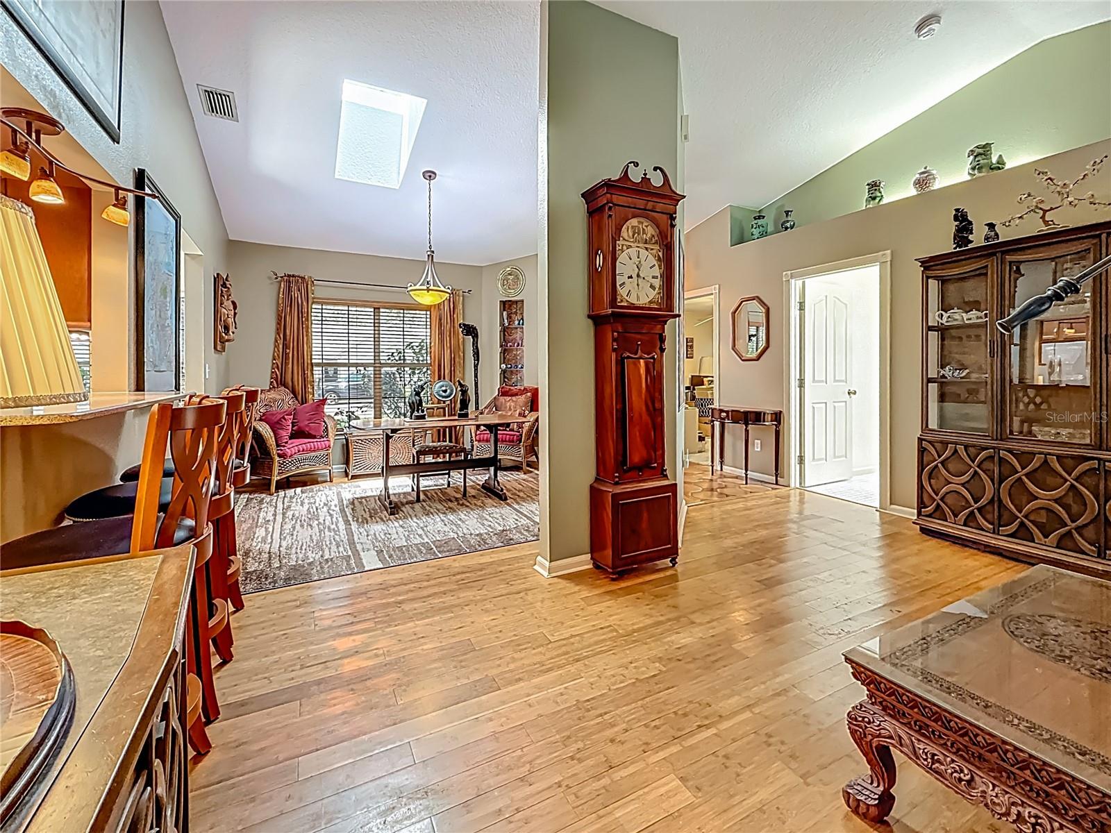 You are the entryway to  the Primary Suit, view is into part of the living room & into the dining room. The open door to your right is the hall bath ( which is also the Jack n' Jill bath for bedrooms 2 & 3) Here you get a better view of the shelving with lights (above the door & china cabinet), as well as the skylight in the dining room.