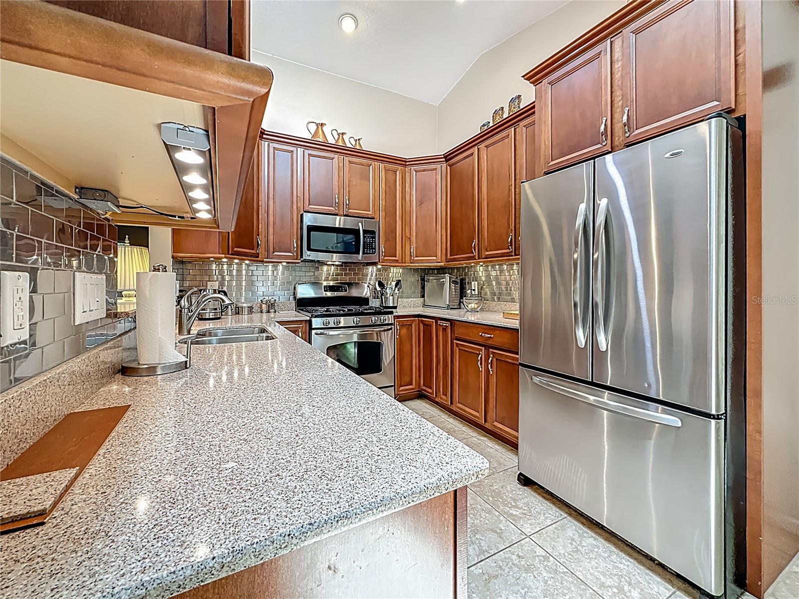 Beautifully updated kitchen with rich wood tones. Extra attention to detail is evident in this update! What you can't see in the pictures: There is ambient lighting both above the cabinets AND below the cabinets! Crown molding tops the cabinets providing for a very nicely finished look. BOTH the UPPER & LOWER corner cabinets include lazy Susan's! Talk about great use of space! There are also: slide out shelfs, slide out trash container cabinet, slide out spice rack. The range is propane gas with a griddle burner in the center. Behind you is the eating space in this kitchen.