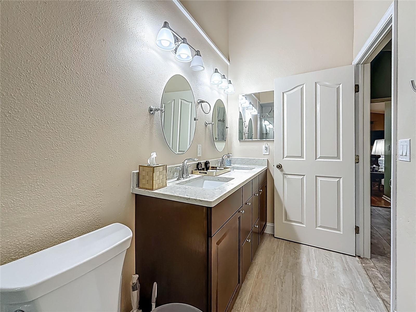 Updated Primary Bedroom en-suite bath with double vanities & tile flooring. Your back is to the shower.