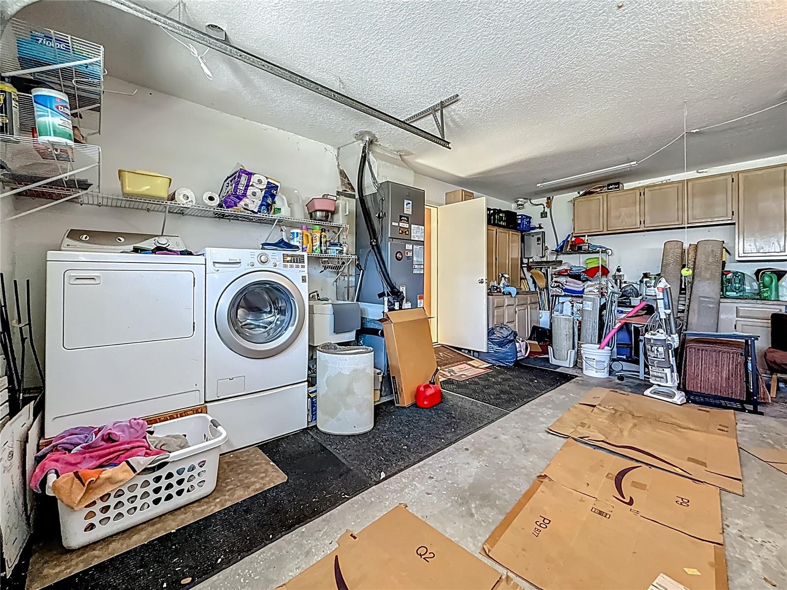 LARGE garage. Yes, there are lots of items in here. Seller IS moving, after all ;-) Washer & propane gas dryer convey. TANKLESS WATER HEATER in the back corner. Plenty of storage cabinets. To the right of the longest upper cabinet is a storage alcove with metal shelving racks (that conveys) for all your storage needs!