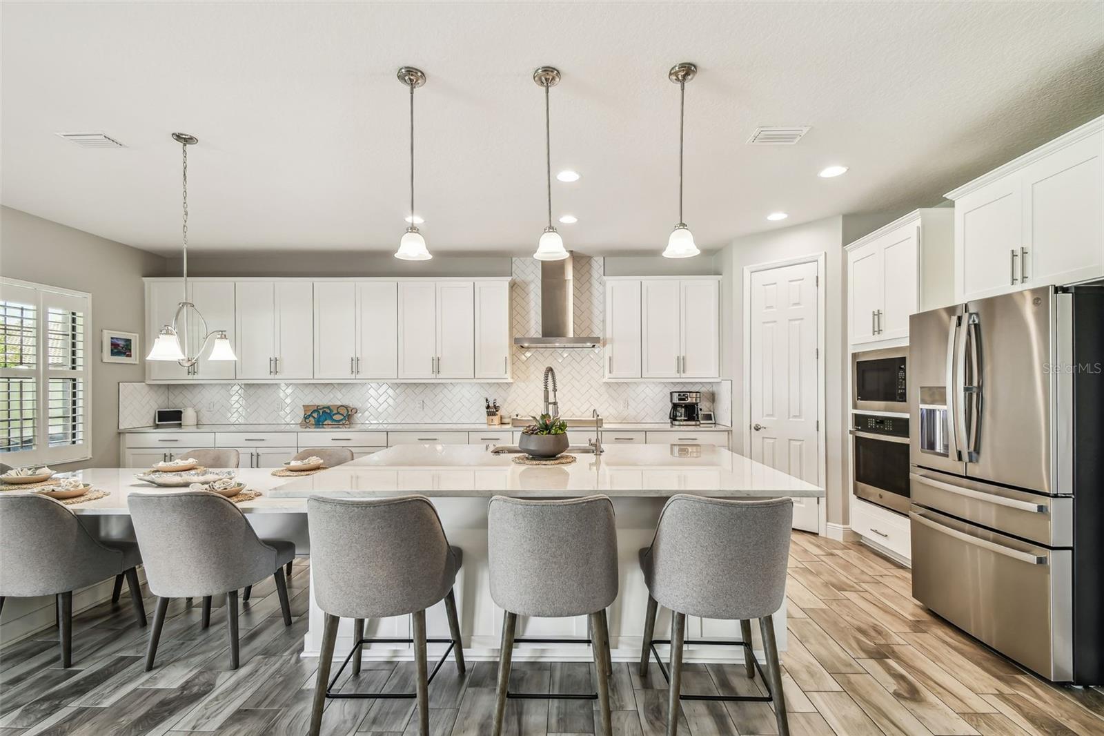 Upgraded Gourmet Kitchen w/Gas Range, SS Appliances & Hood, Built-in Oven & Microwave, Extended Cabinets, Ultra Island, Tile Backsplash, Quartz Countertops, R/O Water Filtration, Walk-in Pantry, & Plantation Shutters