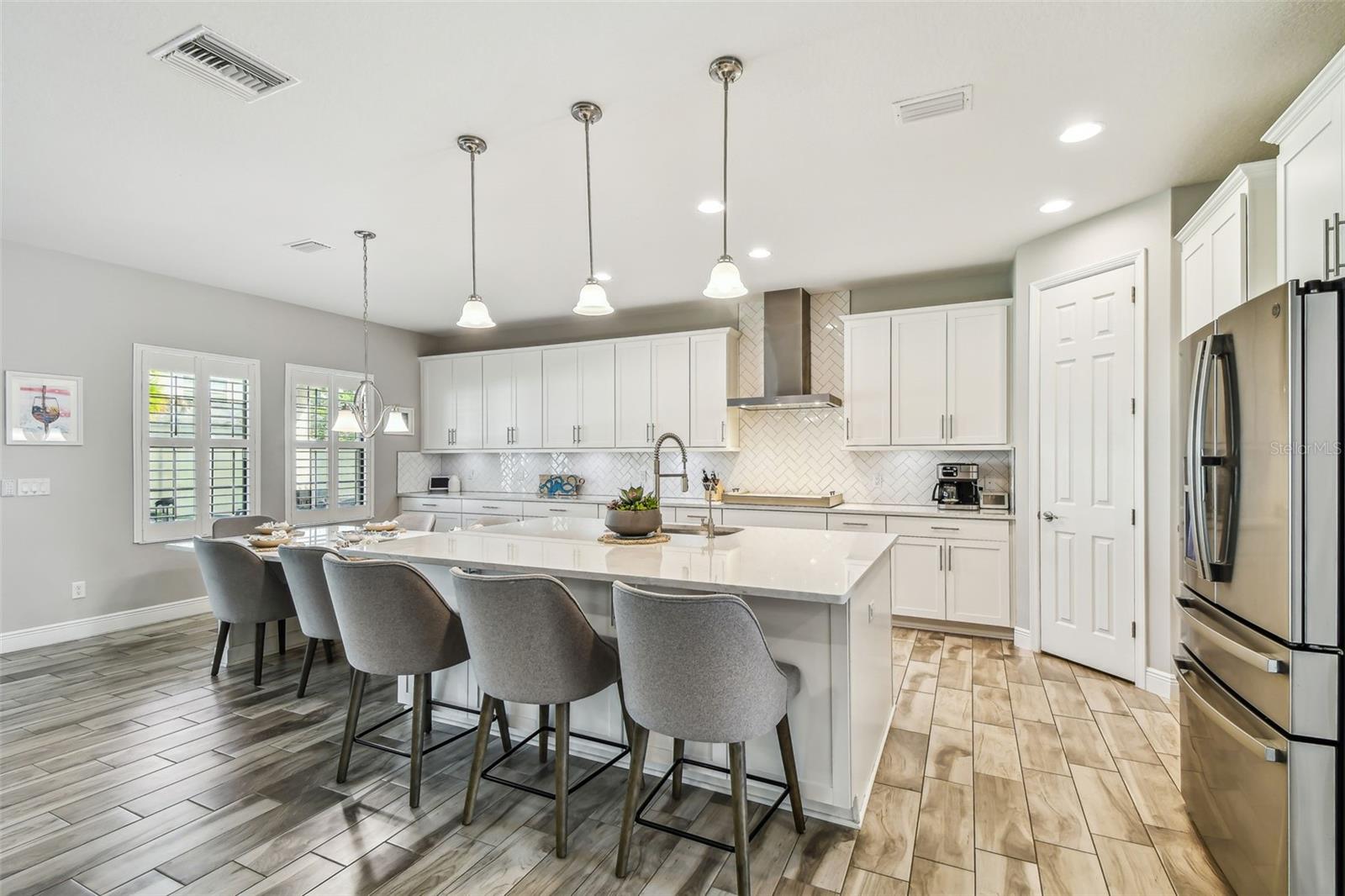 Upgraded Gourmet Kitchen w/Gas Range, SS Appliances & Hood, Built-in Oven & Microwave, Extended Cabinets, Ultra Island, Tile Backsplash, Quartz Countertops, R/O Water Filtration, Walk-in Pantry, & Plantation Shutters