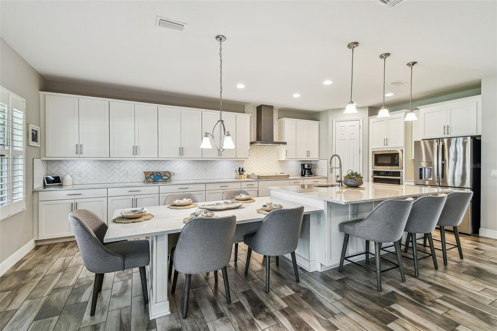 Upgraded Gourmet Kitchen w/Gas Range, SS Appliances & Hood, Built-in Oven & Microwave, Extended Cabinets, Ultra Island, Tile Backsplash, Quartz Countertops, R/O Water Filtration, Walk-in Pantry, & Plantation Shutters
