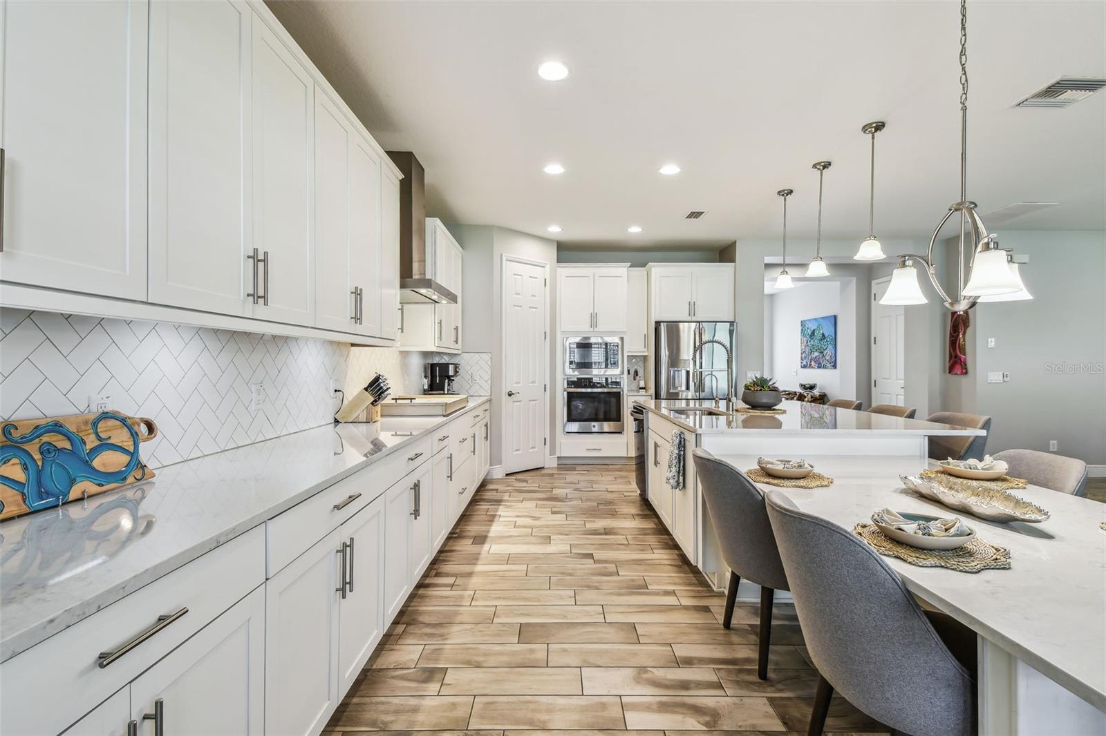 Upgraded Gourmet Kitchen w/Gas Range, SS Appliances & Hood, Built-in Oven & Microwave, Extended Cabinets, Ultra Island, Tile Backsplash, Quartz Countertops, R/O Water Filtration, Walk-in Pantry, & Plantation Shutters