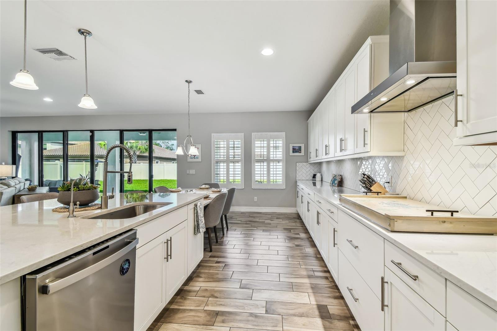 Upgraded Gourmet Kitchen w/Gas Range, SS Appliances & Hood, Built-in Oven & Microwave, Extended Cabinets, Ultra Island, Tile Backsplash, Quartz Countertops, R/O Water Filtration, Walk-in Pantry, & Plantation Shutters