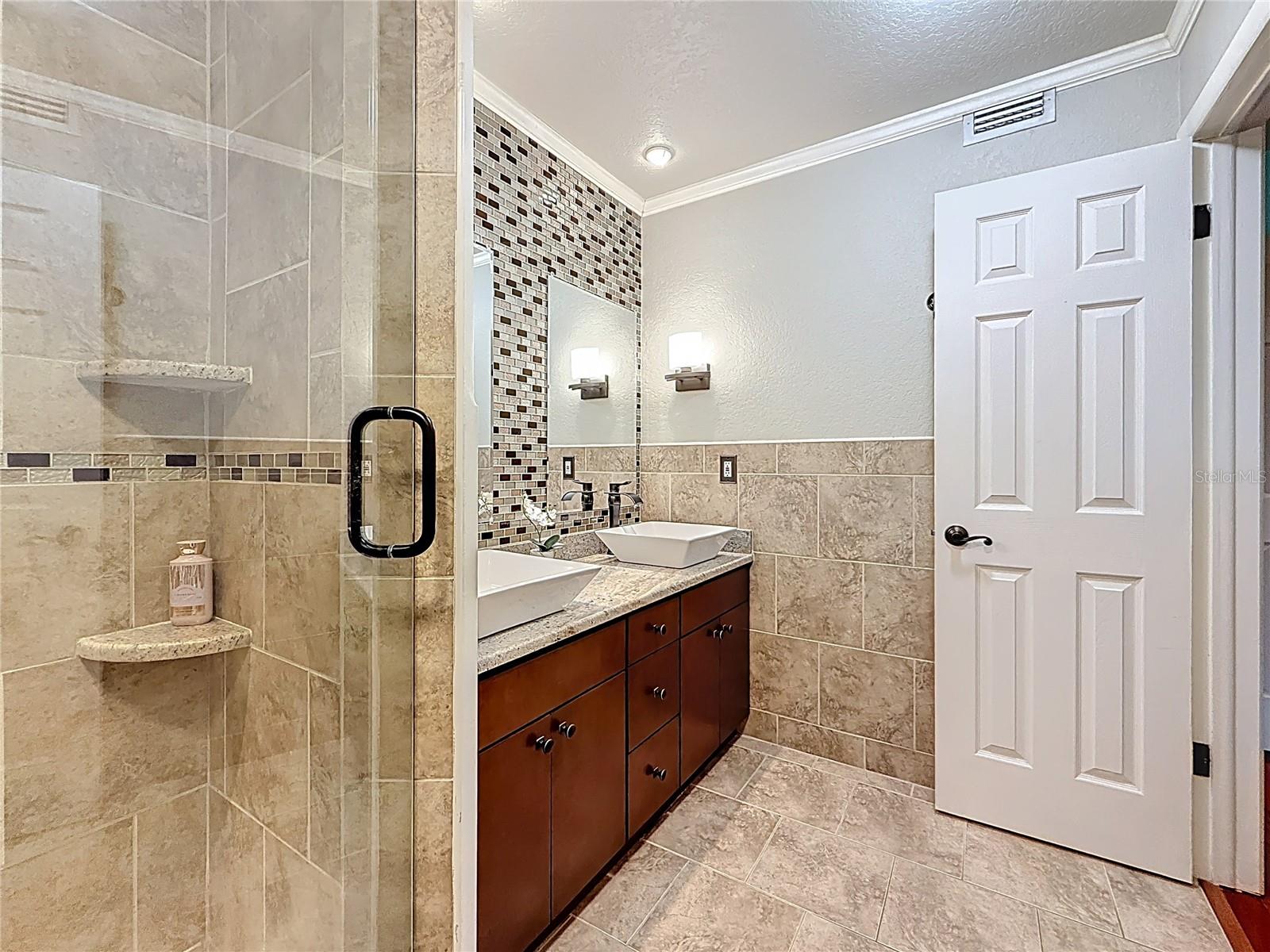 Ensuite barhroom with glass frame shower, granite top vanity and double sinks