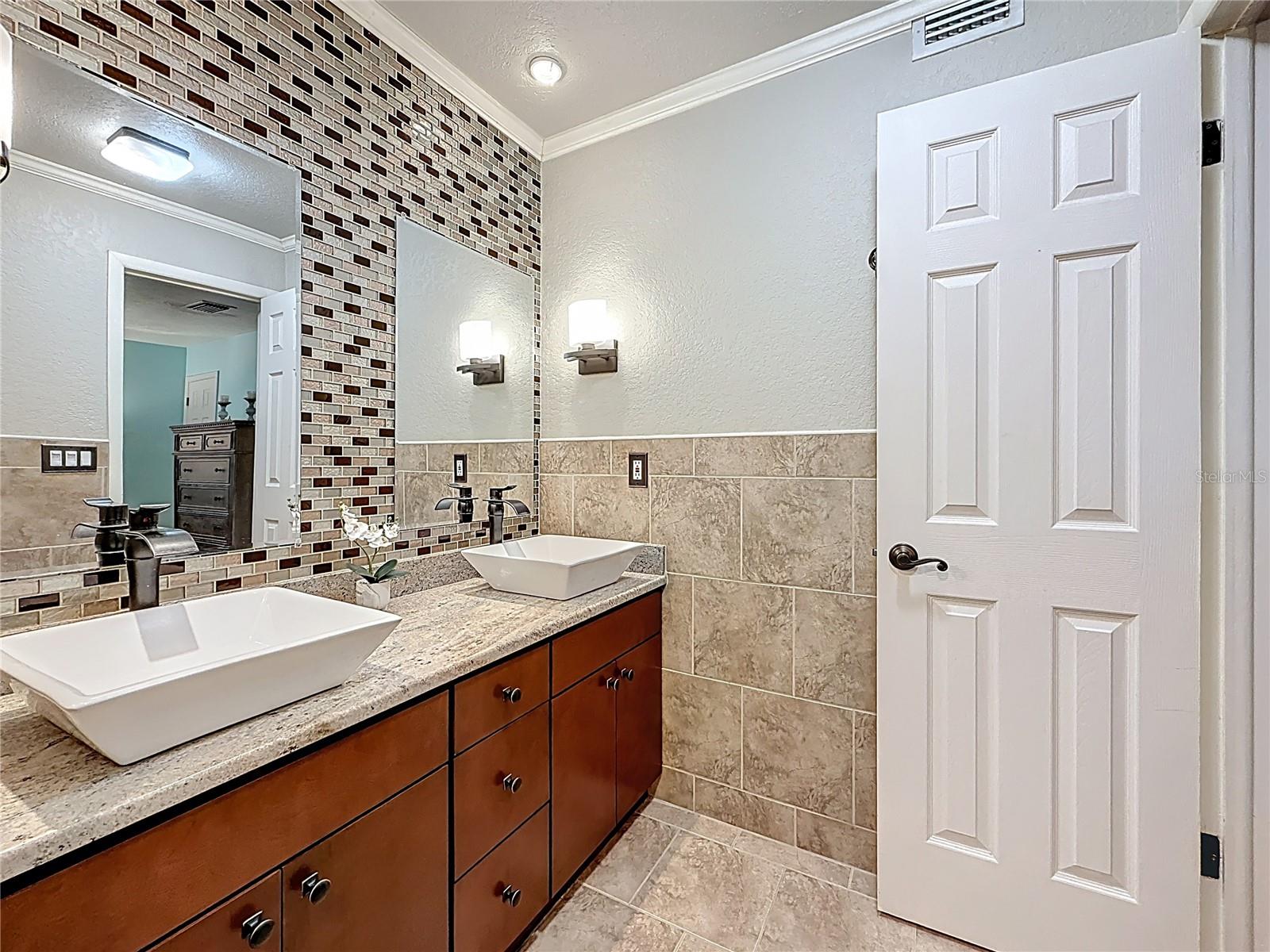 Ensuite barhroom with glass frame shower, granite top vanity and double sinks