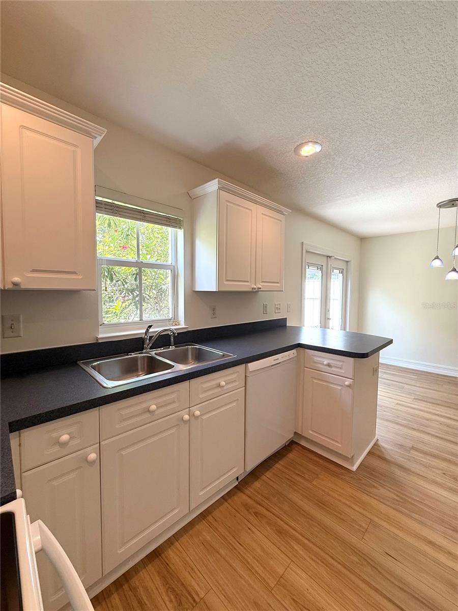 Step into this charming kitchen where style meets function — sleek blue countertops add a bold pop of color, perfectly complemented by a cozy bar with room for two. Whether you're sipping morning coffee or sharing a late-night snack, this inviting space is made for connection and comfort.