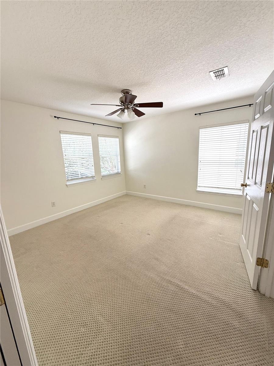 Bright and inviting, this primary bedroom features three large windows that flood the space with natural light. A peaceful retreat with plenty of room to relax, recharge, and wake up to sunshine every morning.