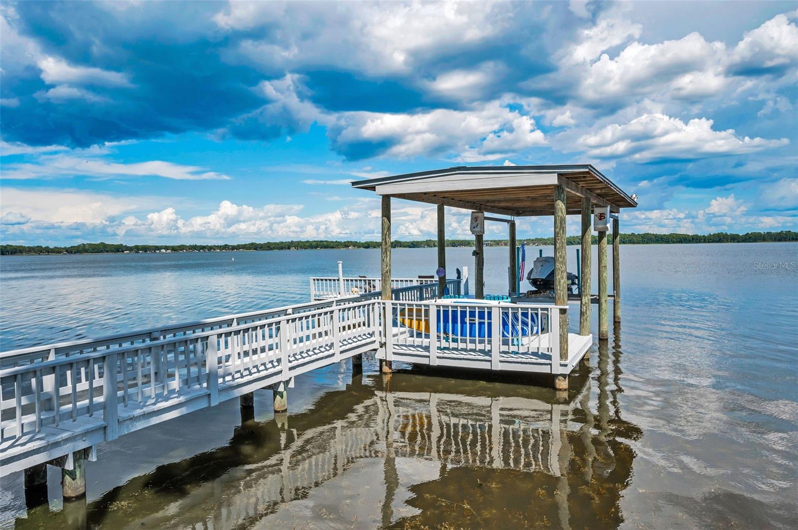 A wonderful dock featuring a lift, covered area, and sun/fishing deck