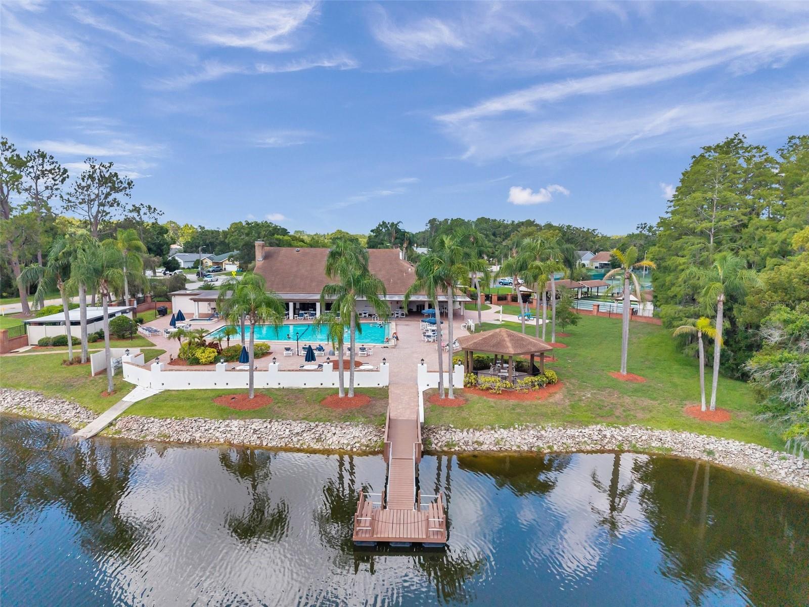 View of the dock behind the community center, the gazzebo, heated pool with a hot tub.