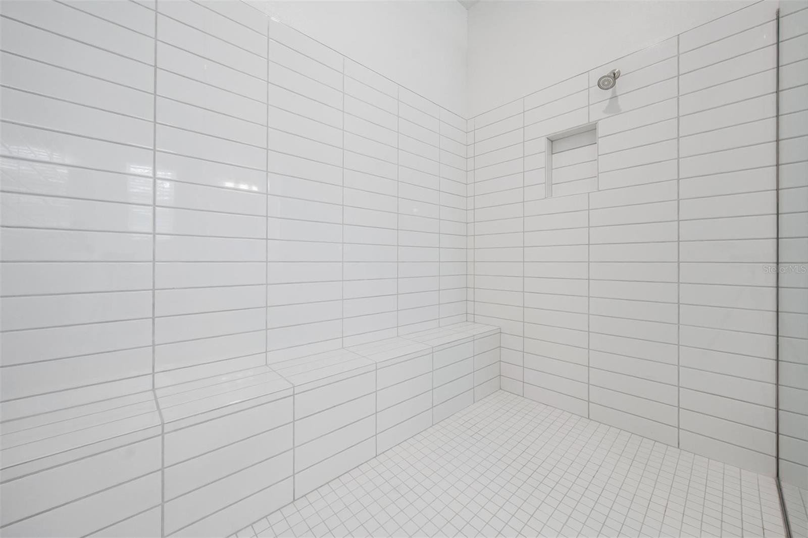 Plenty of room in this shower that includes a bench seat and shampoo niche.